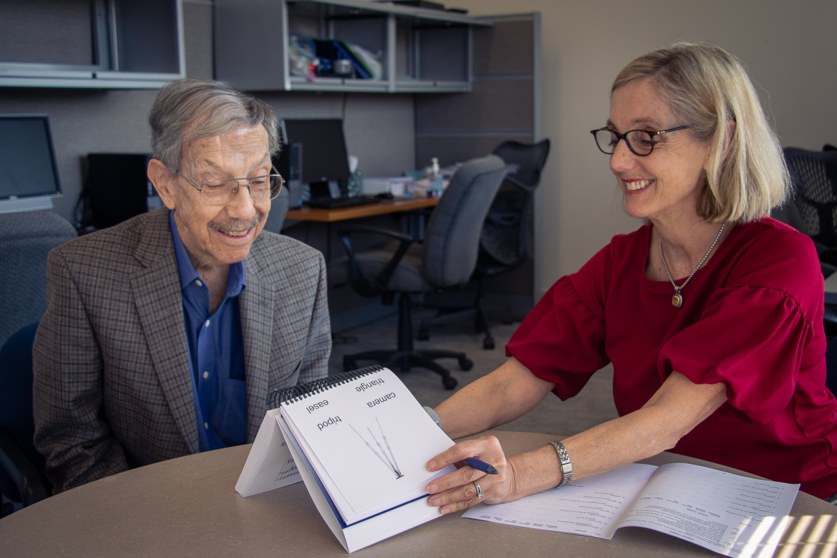 Researcher showing older man tex and image cards